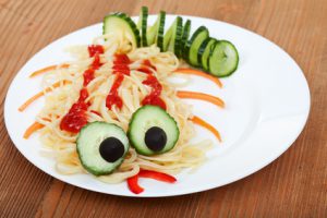 Creative pasta dish with cucumber creature - on wooden table